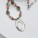Handcrafted necklace with Rhodochrosite and Labradorite beads, silver accents, and an embossed pewter pendant on a 20-inch strand.